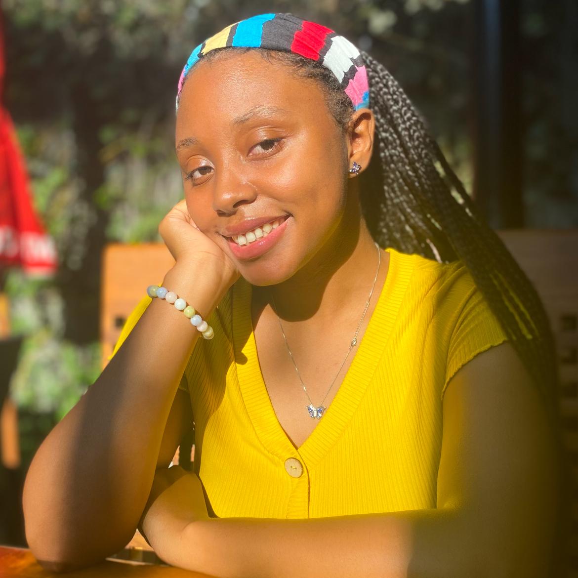 Photo of Janiya wearing a yellow top, smiling at the camera.