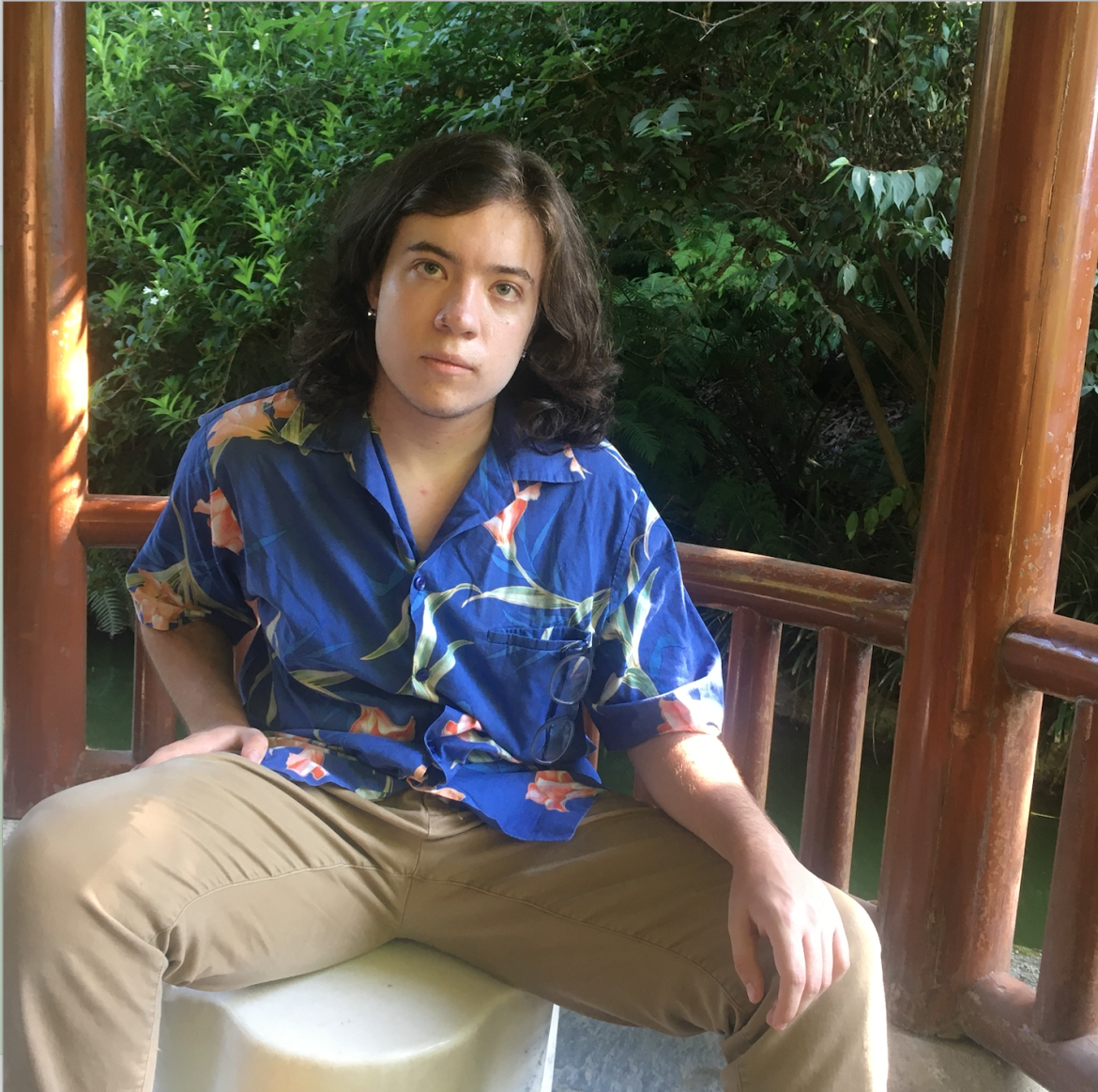 Photo of Evan sitting down, wearing a blue shirt and khaki pants.