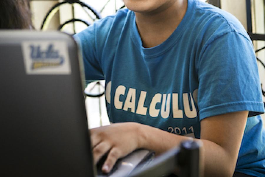 A student in a UCLA t-shirt typs on a laptop.