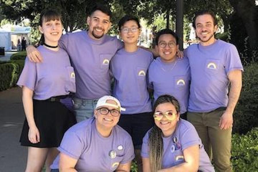 Group photo of the LGBT undergraduate and graduate student interns wearing purple shirts with a rainbow on the breast pocket
